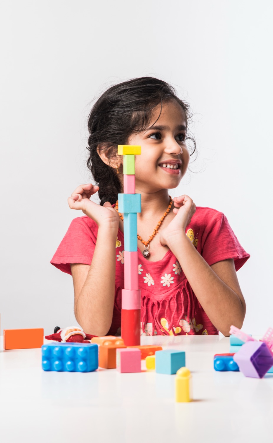 A girl building a tower from colourful blocks